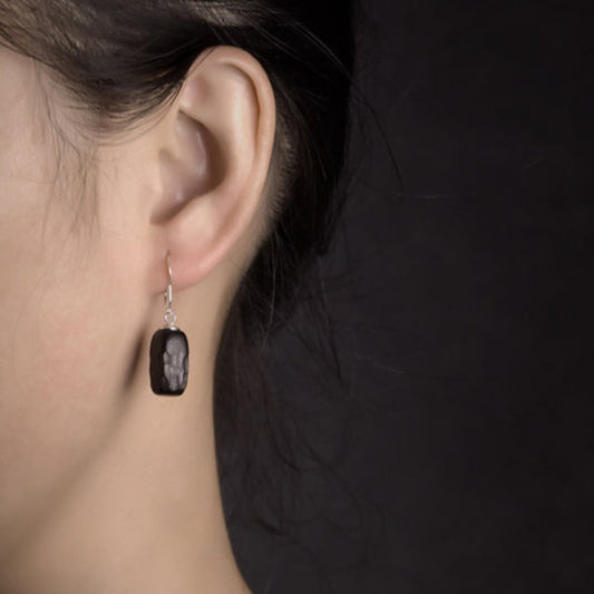 The contrast between the rich ebony wood and the cool, bright silver creates a striking and sophisticated look that is perfect for any occasion. The smooth texture of the wood and the polished silver surface catch the light beautifully, making these earrings a true statement piece